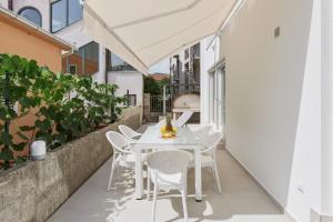 un patio al aire libre con una mesa y sillas blancas en Petrovic apartmani en Tivat
