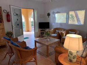 a living room with chairs and a table and a television at Casa Carmencita, immersa nel verde a pochi passi da mare in Es Caló