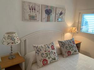 a bedroom with a bed with two pillows and a lamp at Casa Carmencita, immersa nel verde a pochi passi da mare in Es Caló