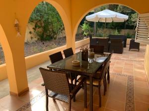 a dining room with a table and chairs and an umbrella at Casa Carmencita, immersa nel verde a pochi passi da mare in Es Caló