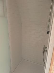 a bathroom with a shower with white tiles at Le mélèze heureux 