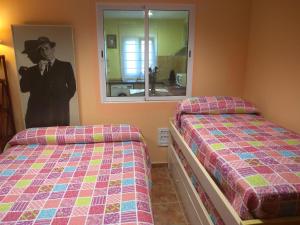 a bedroom with two beds and a picture of a man at La Casuca Azul in Ruiloba