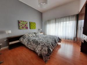 a bedroom with a bed and a large window at Casa c/amplio jardín, garage y parrilla. in Tandil