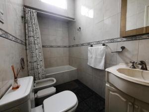 a bathroom with a toilet and a sink and a tub at Casa c/amplio jardín, garage y parrilla. in Tandil +30 photos