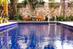 a swimming pool with two chairs and a table in it at Pousada Dharma in Jericoacoara