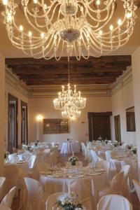 アヴェルサにあるCastello di Casapozzanoの白いテーブルとシャンデリアが並ぶ宴会場