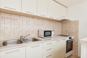 cocina con armarios blancos, fregadero y microondas en Apartments Kotor Sunrise, en Kotor