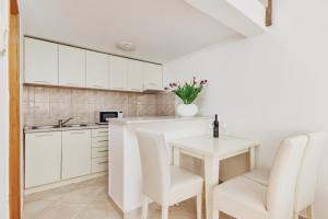 una cocina con armarios blancos y una mesa pequeña con sillas. en Apartments Kotor Sunrise, en Kotor