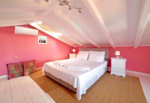 a bedroom with a white bed and a pink wall at Villa Kirki Apartments in Agia Effimia