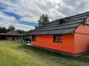 ein orangefarbenes Gebäude mit schwarzem Dach auf einem Feld in der Unterkunft Alojamiento La Victoria in San Rafael