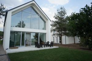 a house with glass doors and chairs on a lawn at Szklane Domy ! in Junoszyno