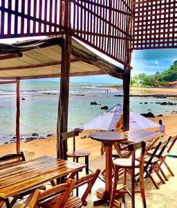 Pé na Areia في بايا فورموزا: طاولة وكراسي على شاطئ به مظلة