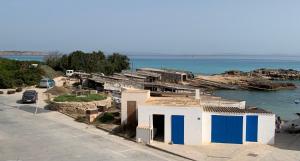 a small house with blue doors on the side of the water at Casa Carmencita, immersa nel verde a pochi passi da mare in Es Caló