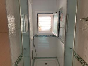 a small bathroom with a shower and a window at Casa Carmencita, immersa nel verde a pochi passi da mare in Es Caló +29 photos
