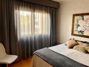 1 dormitorio con ventana, cama y silla en Locflat Mirante 211 Centro Gramado, en Gramado