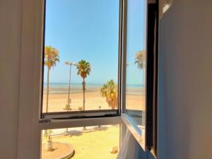 ventana con vistas a la playa y a las palmeras en Apto. Trafalgar, playa de la Cachucha. WiFi, A/C, en Puerto Real