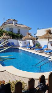 una gran piscina con sillas y sombrillas en Hostal Casa Arco Iris (Playa), en Los Caños de Meca