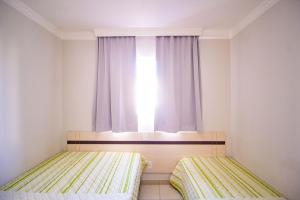 two beds in a small room with a window at Apart Hotel no Rio Quente- Cond. Águas da Serra in Rio Quente