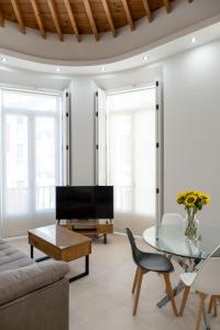een woonkamer met een bank en een glazen tafel bij INMálaga Santos Suites 2 in Málaga