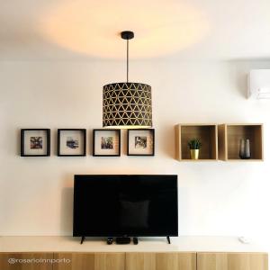 a living room with a television and a pendant light at rosario inn porto in Porto
