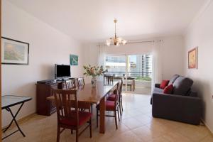a dining room and living room with a table and chairs at Quarteira Beach iii in Quarteira