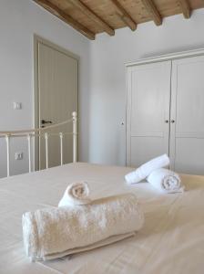 biała sypialnia z łóżkiem i ręcznikami w obiekcie Traditional suites in Chora Kythnos #3 w mieście Kitnos