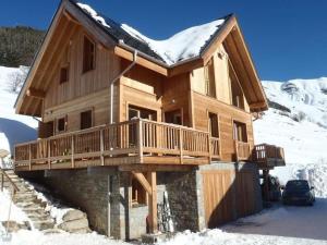 a log cabin with a deck in the snow at Chalet La Ruche in Saint-Sorlin-dʼArves