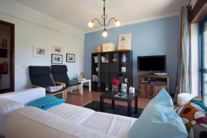 ein Wohnzimmer mit einem weißen Sofa und einem TV in der Unterkunft Sao Bernardino Beach House in Atouguia da Baleia