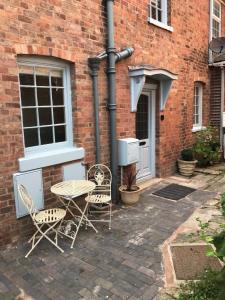a patio with a table and chairs in front of a brick building at Clerks Cottage in Upton upon Severn