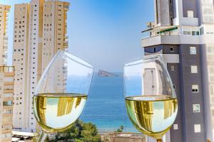 dos copas de vino blanco en un balcón con el océano en See the Sea Miramar apartment - 150m to the beach en Benidorm