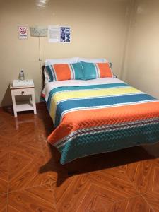 a bedroom with a bed with an orange and blue blanket at Hostal Cumbres Andinas in Ibarra