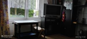 sala de estar con TV, mesa y ventana en Mini domek jednopokojowy en Suwałki