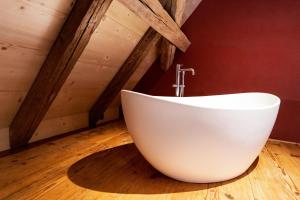 eine weiße Badewanne auf einem Holzboden im Bad in der Unterkunft Resort Schloss Rued in Schlossrued