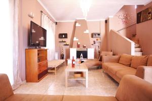 a living room with a couch and a tv at Alice Maisonette & Studios in Adamantas