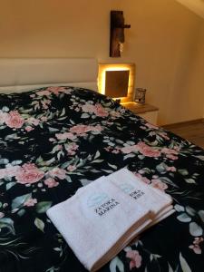 a bed with a floral blanket with two towels on it at Zatoka Marina in Mechelinki