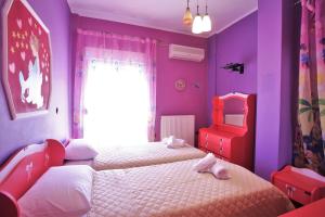 a purple bedroom with two beds and a chair at Alice Maisonette & Studios in Adamantas