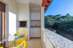 a kitchen with a table and yellow chairs and a window at Apto com banheira de imersão - Stay House in Canela