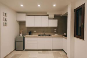 法薩諾的住宿－Suite Matteotti，厨房配有白色橱柜和水槽