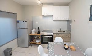 a kitchen with white cabinets and a table and a sink at iLposto Down in Kavála
