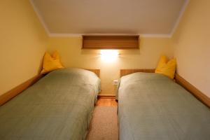 2 camas en una habitación pequeña con almohadas amarillas en Ländliches Ferienhaus, en Kötschach-Mauthen