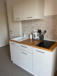 Apartments CLIFF Piran في بيران: مطبخ مع دواليب بيضاء ومغسلة