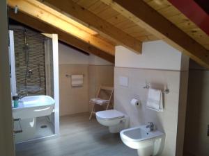 La salle de bains est pourvue de toilettes blanches et d'un lavabo. dans l'établissement Dreaming Feriolo - mansarded apartment by Danilo Apartments, à Baveno