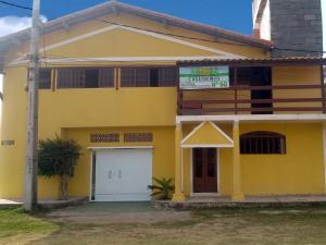 una casa amarilla con garaje blanco en Pousada das Casuarinas en Saquarema