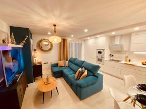uma sala de estar com um sofá azul e uma cozinha em Alicante - Turquesa Del Mar Suites - Luxury em Orihuela