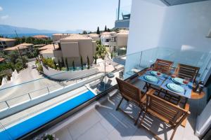 balcón con mesa, sillas y piscina en Odysseus journey en Nikiana