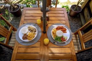 a wooden table with two plates of food and drinks at Pousada Y-Goá in Bertioga