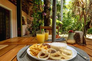 a plate of food with fries and a glass of orange juice at Pousada Y-Goá in Bertioga