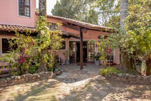 an exterior view of a pink house with plants at Pousada Y-Goá in Bertioga