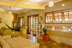 a living room with a couch and a room with books at Pousada Y-Goá in Bertioga
