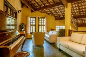a living room with a piano and a couch at Pousada Y-Goá in Bertioga
